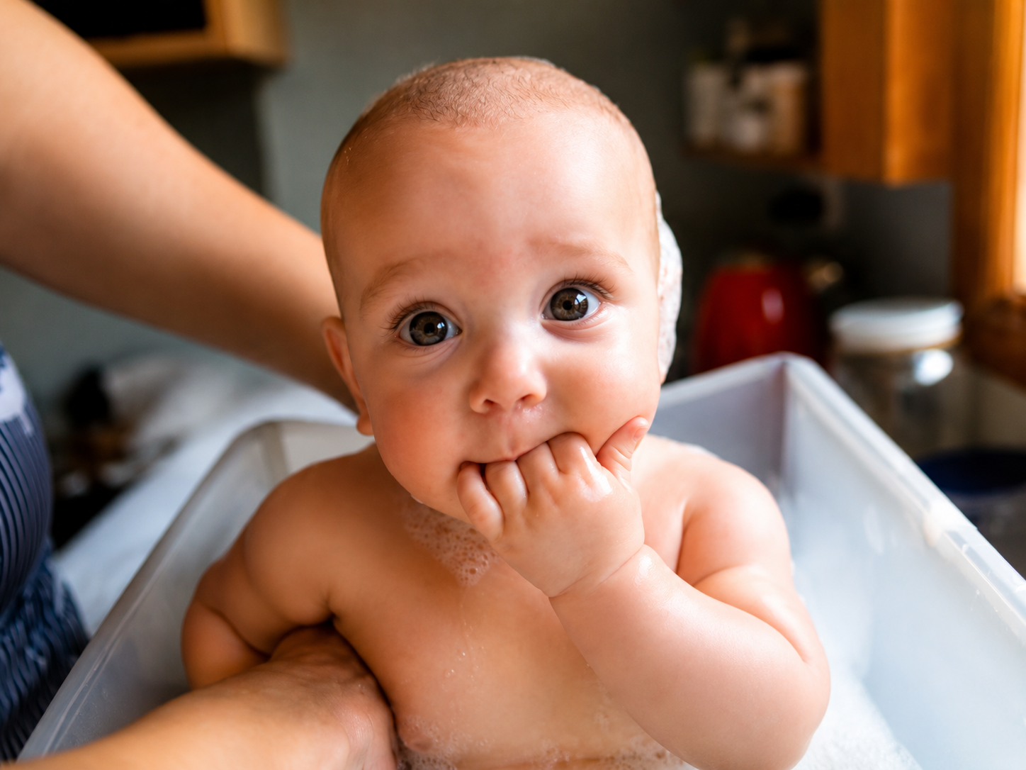 A newborn being gently bathed at home